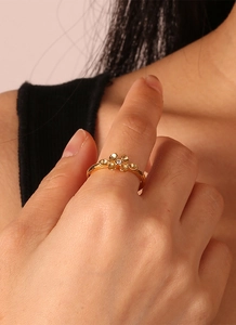 Macro detail of gold flower ring with clover petals and sparkling zircon stones on finger