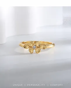 Macro shot of 18K gold clover ring featuring brushed metal petals and center zircon