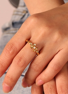 Close-up of golden clover ring with brushed petals and zircon inlay on model's hand