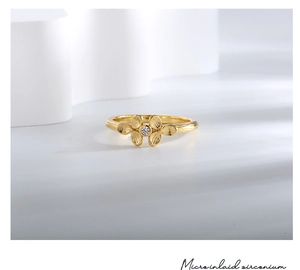 Macro view of flower ring showing micro-inlaid zirconium and brushed gold texture