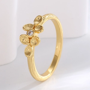 Elegant gold clover flower ring with cubic zirconia on a minimalist white background