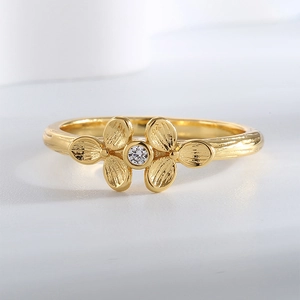 Elegant gold clover ring with hammered texture and sparkling zircon center stone