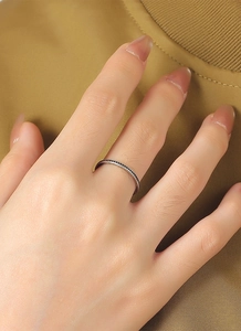 Nahaufnahme eines minimalistischen Silberrings mit schwarzen Punkten am Finger