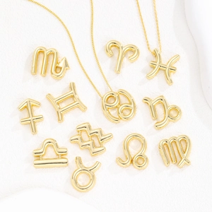 Golden 12 zodiac bubble pendant necklaces displayed on white textured stone background