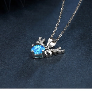 Detail of silver reindeer necklace featuring a round blue zircon and crystal deer horn