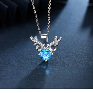 Detail of deer antler necklace with large blue zircon inlay on navy textured background