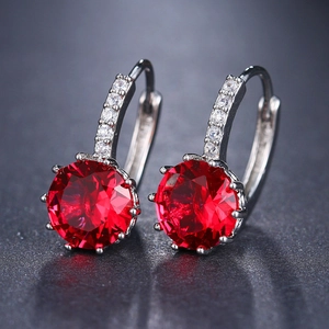 Macro shot of silver earrings with brilliant round red ruby zircon and micro-paved gems