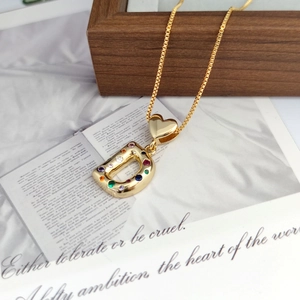 Macro detail of gold D letter pendant with colorful gemstones and heart link