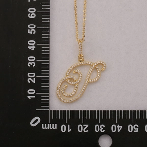 Macro view of cursive letter P pendant with micro-pave cubic zirconia on a gold chain