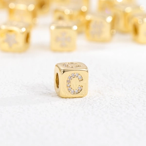 Nahaufnahme der 18k vergoldeten Würfelperle mit Buchstabe C und glitzernden Zirkonia