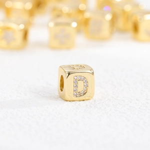 Detail eines 18k vergoldeten Würfelanhängers mit Zirkonia-Besatz und Buchstabe D