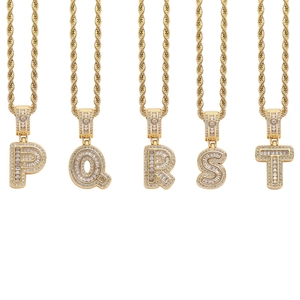 Detailed view of gold-plated twisted chains with iced-out cubic zirconia alphabet pendants