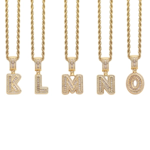 Detail of gold hip-hop initial necklaces with cubic zirconia baguette stones on rope chains