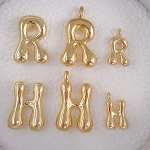 Macro detail of glossy golden balloon style initial pendants for fashion necklace