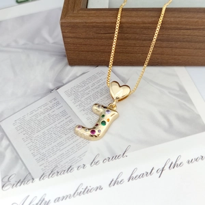Close-up of golden letter J pendant with vibrant colorful crystals and heart clasp