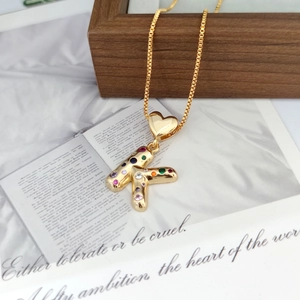 Detailed close-up of a golden heart necklace with a multicolor zircon letter K pendant