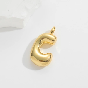 Macro detail of 3D balloon letter C pendant in polished gold with metallic sheen
