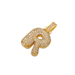 Macro shot of 18k gold plated letter R pendant with iced out cubic zirconia stones