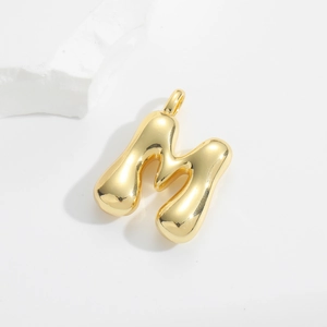 Detailed macro view of a 3D bubble style gold letter M pendant with mirror finish