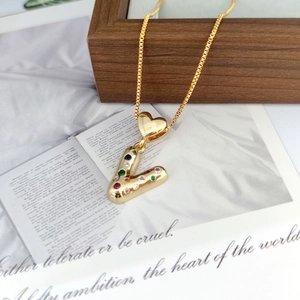 Detailed macro view of a gold-tone letter V pendant with colorful stones on a box chain