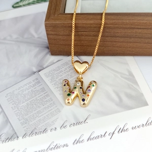 Detail of a gold letter W pendant featuring colorful zircon stones and a heart-shaped bail