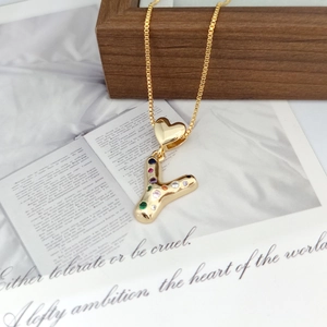 Detail of gold letter Y necklace pendant with colorful cubic zirconia on a wooden surface