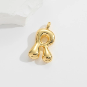 Detailed macro view of a 3D bubble letter R gold pendant with mirror polished finish