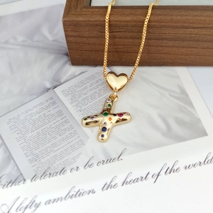 Detail of gold letter X heart pendant with multicolor zircon stones on a wooden box