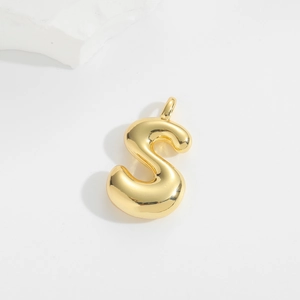 Macro detail of high-polished gold balloon letter S pendant with mirror finish