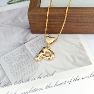 Detail of a golden bubble letter P pendant with colorful zircon stones on a heart clasp