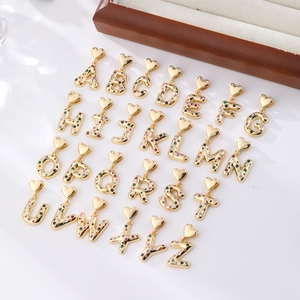 Golden A-Z alphabet pendants with colorful cubic zirconia and heart hooks on white background