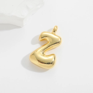 Macro view of a 3D puffy balloon style gold pendant with a polished mirror finish