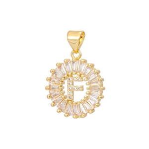 Macro detail of 18k gold pendant with letter F and baguette cubic zirconia stones