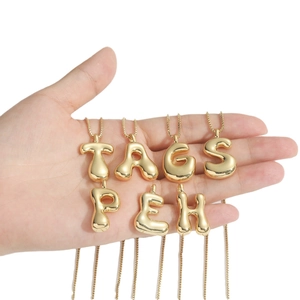 Fashionable golden puffy balloon letter pendants with a polished mirror finish on hand