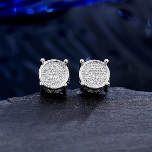 Macro shot of silver micro-paved round zircon earrings set on a black textured rock