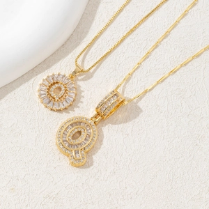 Gold plated letter Q pendant necklace with clear zircon stones on a white background