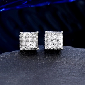 Macro shot of iced out silver square stud earrings with zircons on black stone