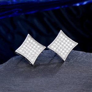 Macro shot of silver diamond rhinstone earrings on dark stone highlighting micro-pave details