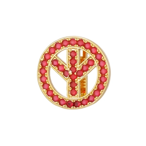 Detailed view of a gold-plated peace sign charm with pavé-set red gemstones on white background