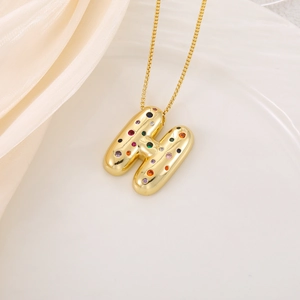 Détail d'un pendentif lettre H en or 3D serti de cristaux multicolores et brillants
