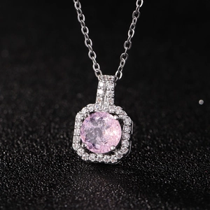 Détail macro d'un pendentif flacon de parfum en argent avec grand zircon rose et cristaux