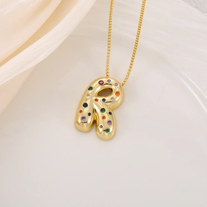 Détail du pendentif lettre R doré gonflé serti de zircons colorés sur chaîne fine