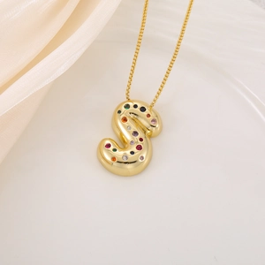 Gros plan du pendentif lettre S dorée avec incrustations de zircons multicolores