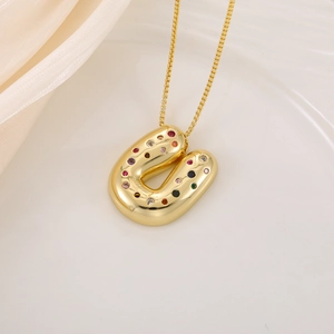 Détail du pendentif lettre U doré serti de zircons multicolores sur soie blanche