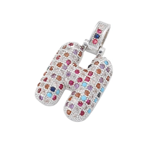 Dettaglio macro del ciondolo in rame a forma di H con cristalli multicolore in micro-pavé