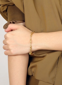 Détail du bracelet trombone plaqué or avec maillons texturés et pendentif rond élégant