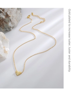 Macro shot of gold plated heart pendant with R engraving on a fine cable chain