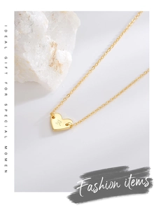 Detailed macro shot of a gold heart pendant with letter R on elegant white stones