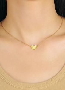 Macro shot of gold-plated heart necklace with engraved letter G on a female model
