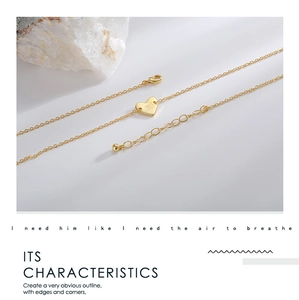 Macro detail of gold plated heart pendant with engraved letter R on a delicate chain